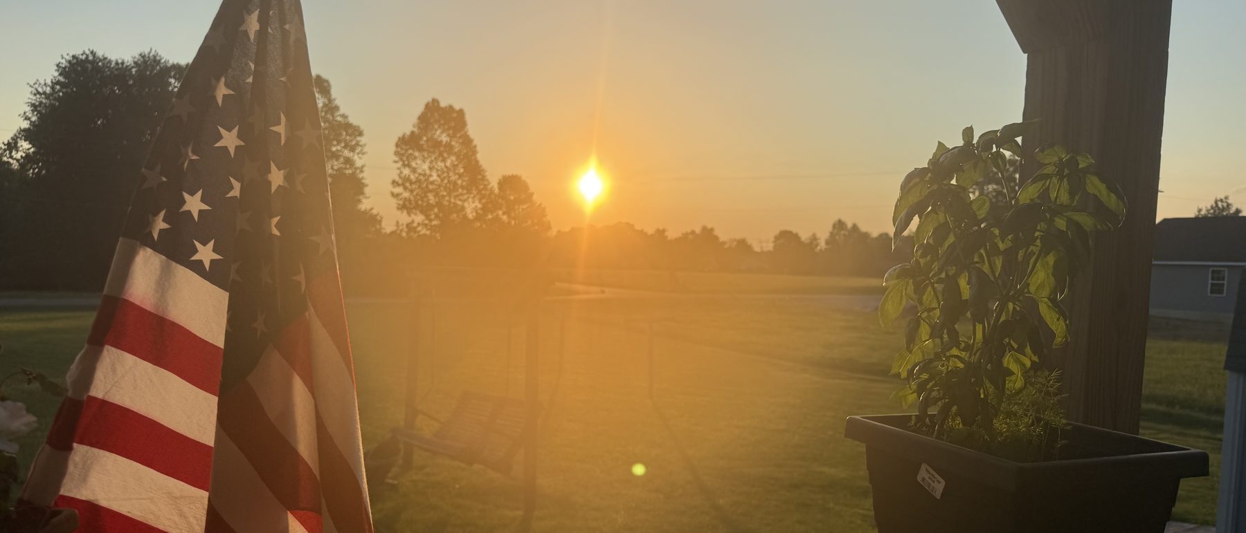 An American flag at sunrise on a porch in Ohio, photographed by Dustin Nimmo